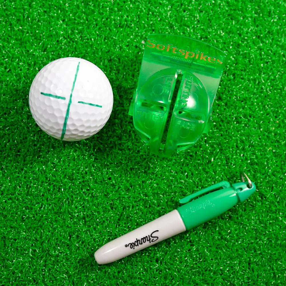 Golf ball, green marking tool, and green Sharpie marker on a green grass-like background