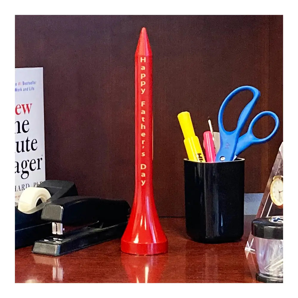 Comically oversized red golf tee with personalized engraving on an office desk