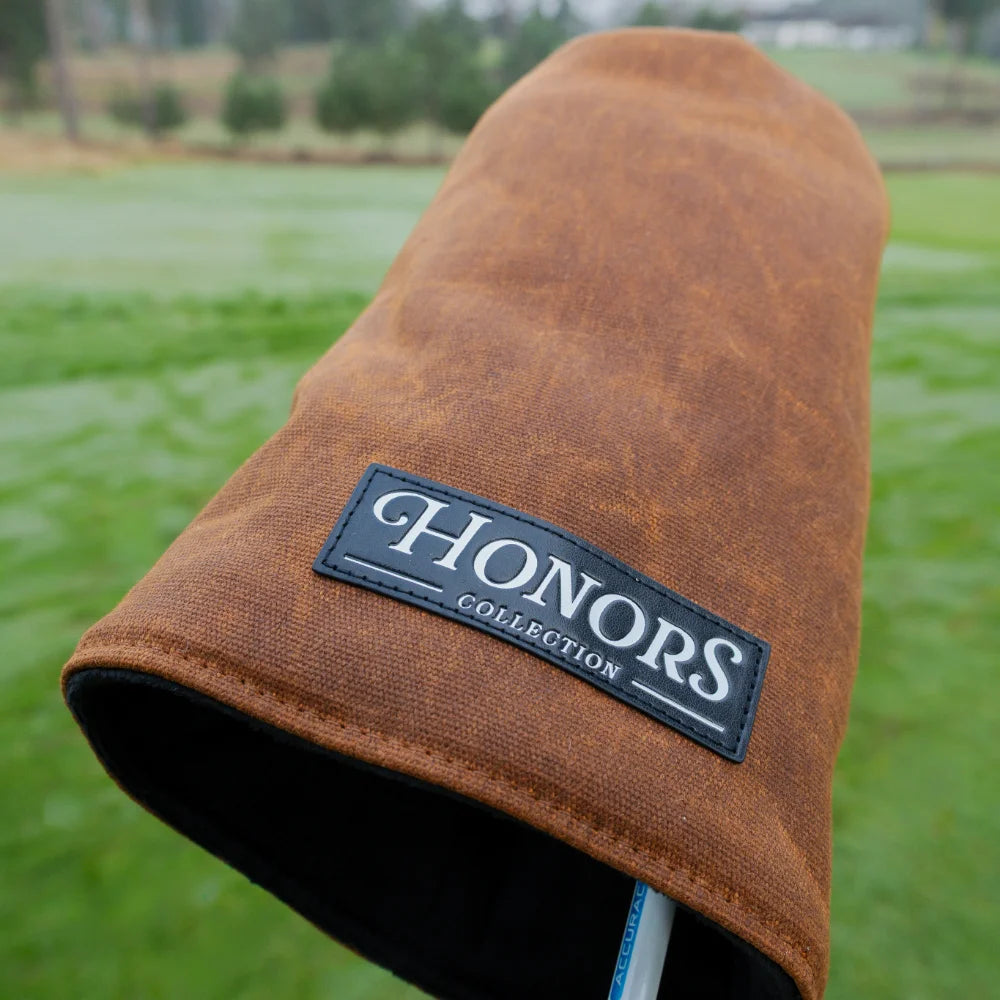 Brown waxed canvas Barrel Fairway Wood headcover featuring a black rectangular patch with the text HONORS COLLECTION, centered on a golf course.